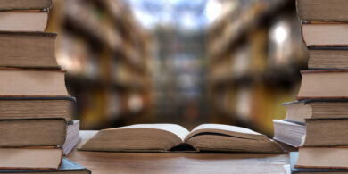 整然と並ぶ専門書と開かれた本がある書庫の風景。人事労務コラムの背景。